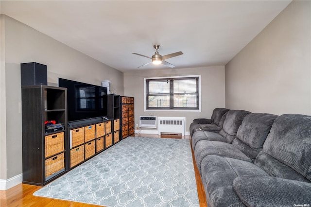 living room featuring radiator, ceiling fan, wood-type flooring, and a wall mounted air conditioner