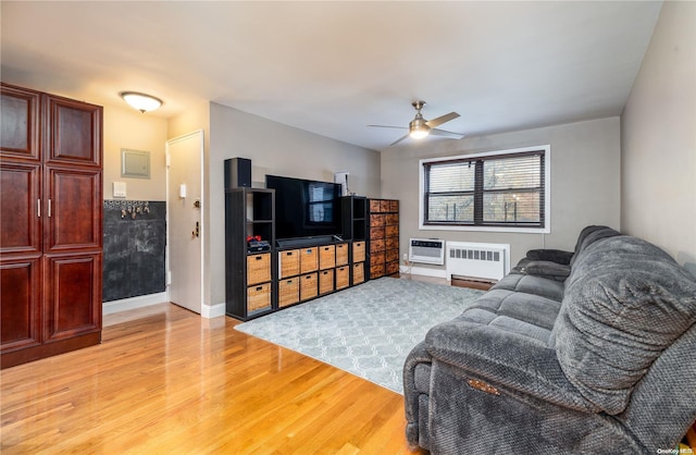 living room featuring a wall mounted air conditioner, ceiling fan, radiator, and light hardwood / wood-style flooring