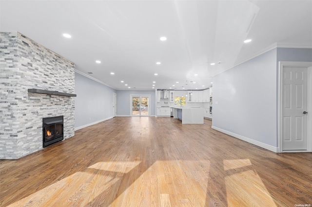 unfurnished living room with a fireplace, light hardwood / wood-style flooring, and ornamental molding