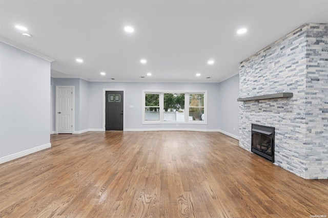 unfurnished living room with a fireplace, light wood-type flooring, and ornamental molding