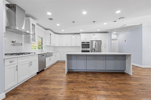 kitchen with white cabinetry, pendant lighting, stainless steel appliances, and wall chimney range hood