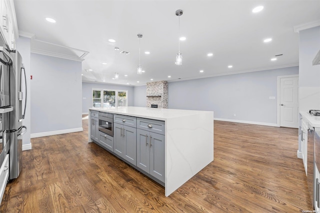 kitchen featuring gray cabinetry, a large island, light stone countertops, dark hardwood / wood-style flooring, and ornamental molding