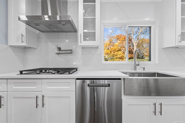 kitchen with white cabinets, wall chimney range hood, sink, and stainless steel appliances