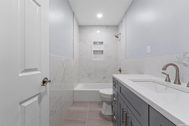 full bathroom with vanity, tiled shower / bath, tile patterned flooring, toilet, and tile walls