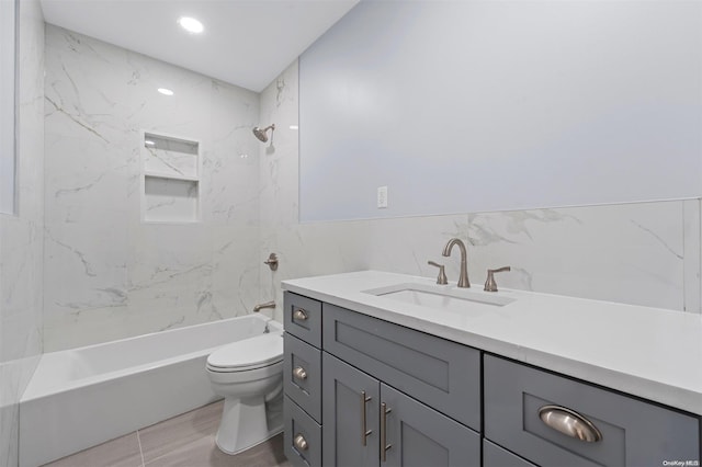 full bathroom with tiled shower / bath combo, toilet, tile walls, and vanity