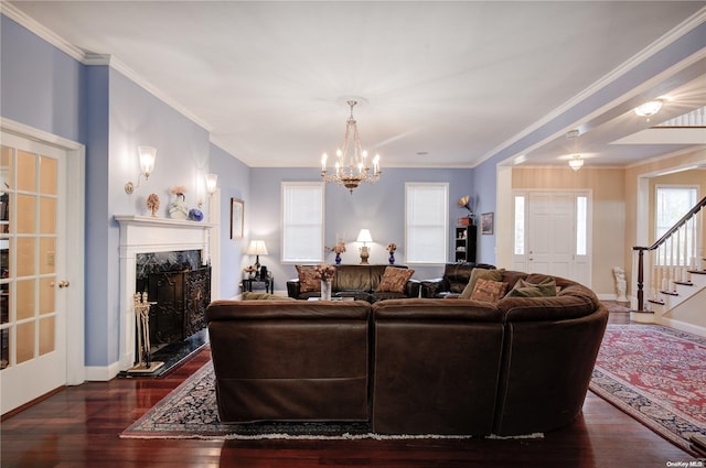 living room featuring dark hardwood / wood-style flooring, crown molding, a fireplace, and an inviting chandelier