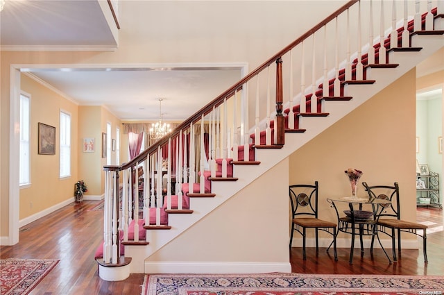 stairs featuring crown molding, wood-type flooring, and an inviting chandelier