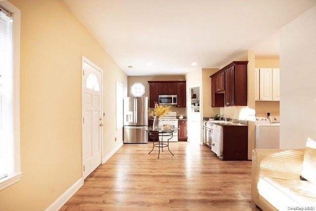 kitchen featuring sink, stainless steel appliances, dark brown cabinetry, washer and dryer, and light wood-type flooring