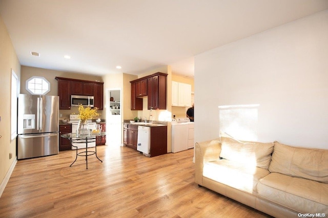 living room with sink, light hardwood / wood-style floors, and washer and dryer