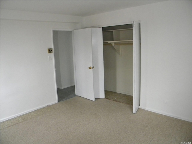 unfurnished bedroom featuring light colored carpet and a closet