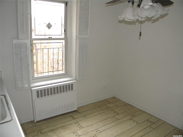 empty room with ceiling fan, radiator, and light hardwood / wood-style flooring