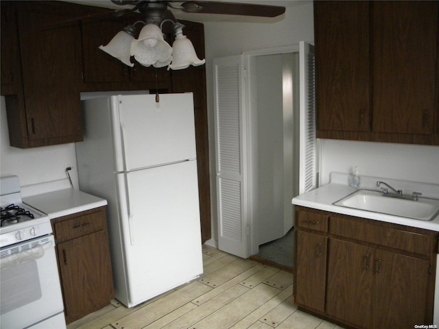 kitchen featuring dark brown cabinetry, sink, white appliances, and light hardwood / wood-style flooring