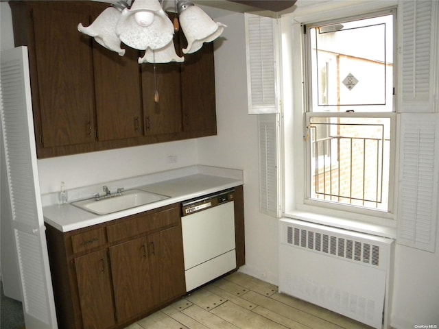 kitchen with white dishwasher, dark brown cabinetry, radiator heating unit, and sink