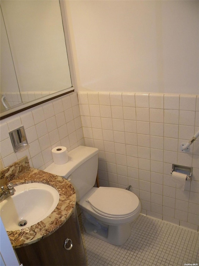 bathroom with tile patterned floors, vanity, tile walls, and toilet