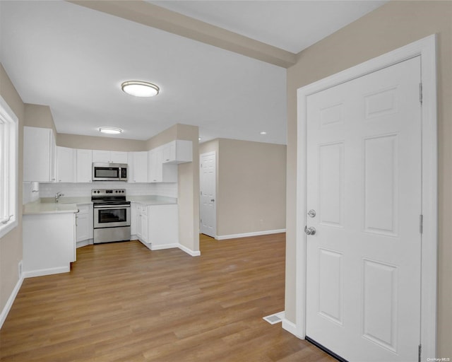 kitchen featuring decorative backsplash, stainless steel appliances, sink, light hardwood / wood-style floors, and white cabinetry