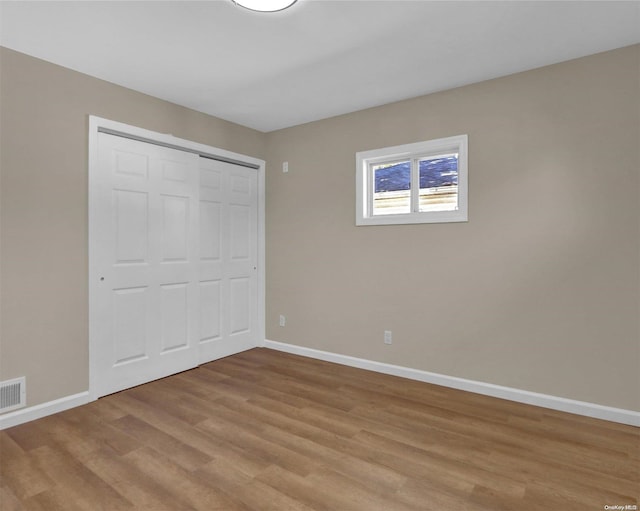 unfurnished bedroom featuring light hardwood / wood-style flooring and a closet