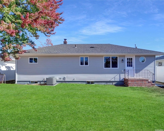 rear view of house with a lawn and cooling unit