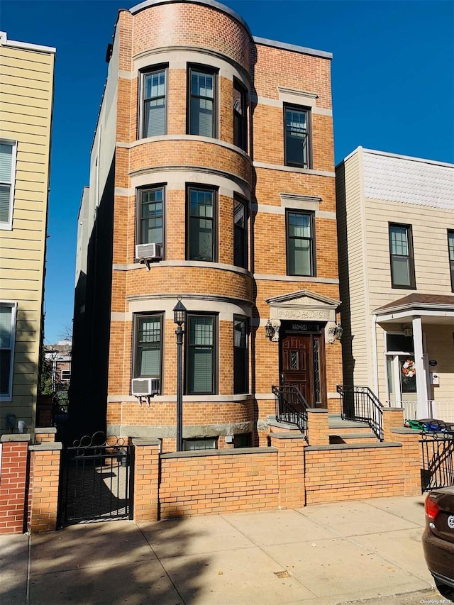 25-54 37th St, Astoria, NY 11103 - view of front facade featuring brick siding, a fenced front yard, and cooling unit