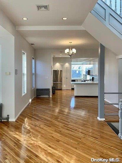 25-54 37th St, Astoria, NY 11103 - unfurnished living room featuring a chandelier, wood finished floors, radiator, and recessed lighting