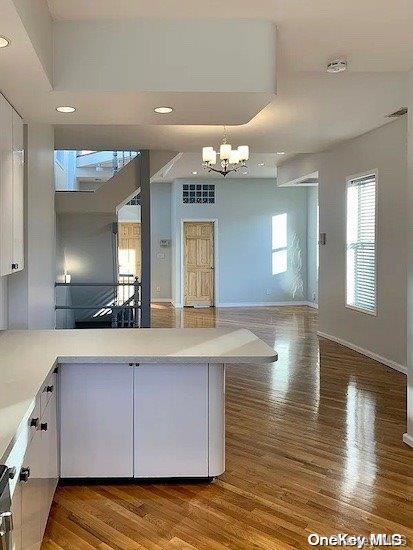 25-54 37th St, Astoria, NY 11103 - kitchen with wood finished floors, white cabinets, a chandelier, light countertops, and open floor plan