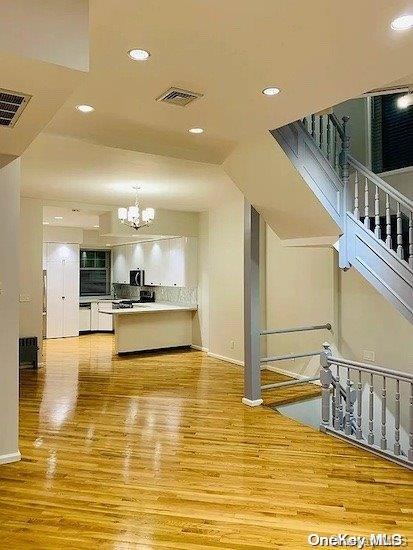 interior space featuring white cabinets, light wood-type flooring, and an inviting chandelier