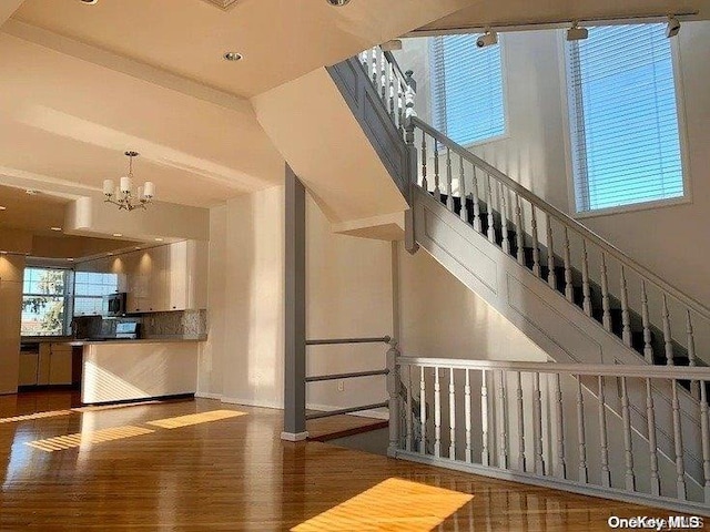 stairs featuring hardwood / wood-style floors and a notable chandelier