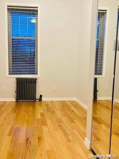 empty room featuring wood-type flooring and radiator