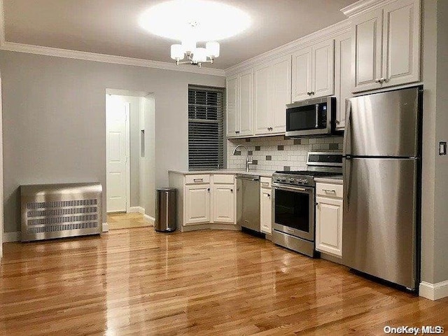 25-54 37th St, Astoria, NY 11103 - kitchen featuring appliances with stainless steel finishes, white cabinetry, crown molding, and a chandelier
