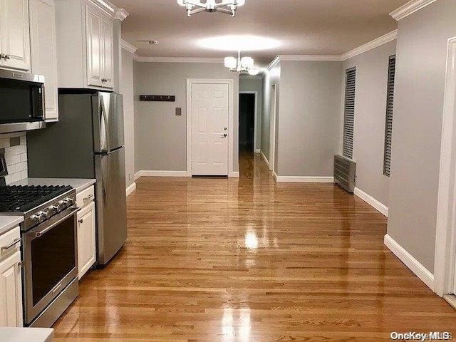25-54 37th St, Astoria, NY 11103 - kitchen with stainless steel appliances, a chandelier, ornamental molding, white cabinets, and light wood-style floors