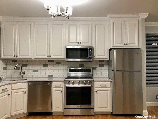 25-54 37th St, Astoria, NY 11103 - kitchen featuring stainless steel appliances, white cabinets, light countertops, a chandelier, and tasteful backsplash