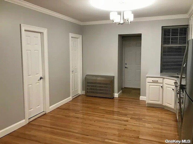 interior space with sink, light wood-type flooring, crown molding, and an inviting chandelier