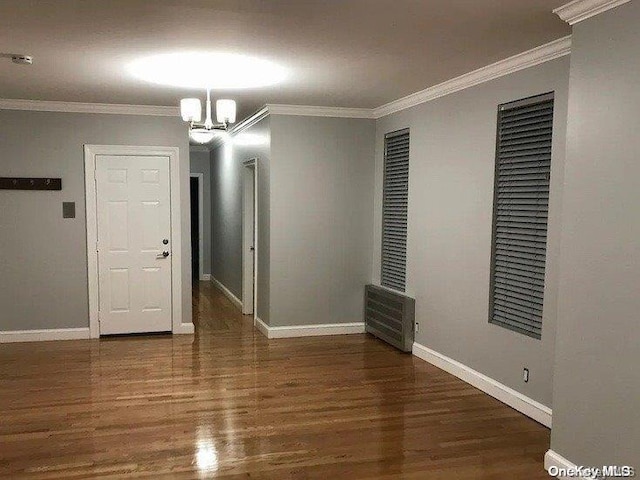 empty room featuring ornamental molding, dark wood-type flooring, and a notable chandelier