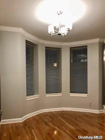 25-54 37th St, Astoria, NY 11103 - spare room featuring a chandelier, wood finished floors, and crown molding