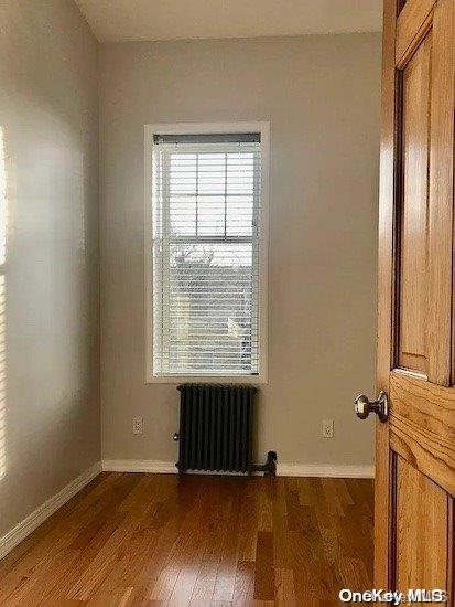 spare room with radiator heating unit and dark wood-type flooring