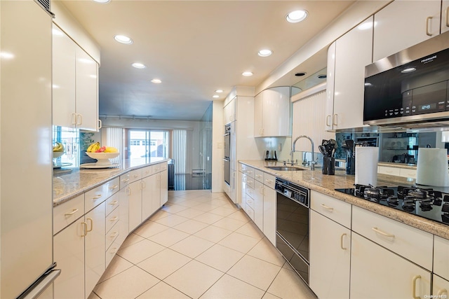 kitchen featuring light stone counters, sink, white cabinets, and black appliances