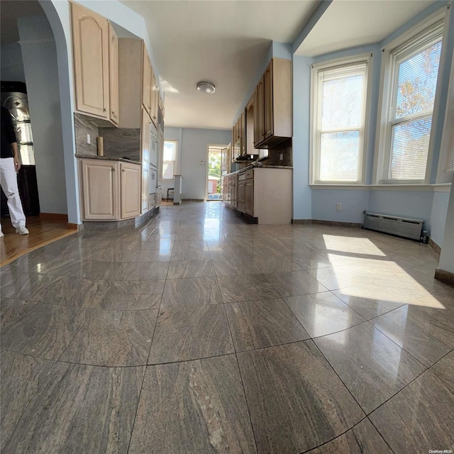 kitchen featuring baseboard heating, backsplash, light brown cabinets, and a healthy amount of sunlight