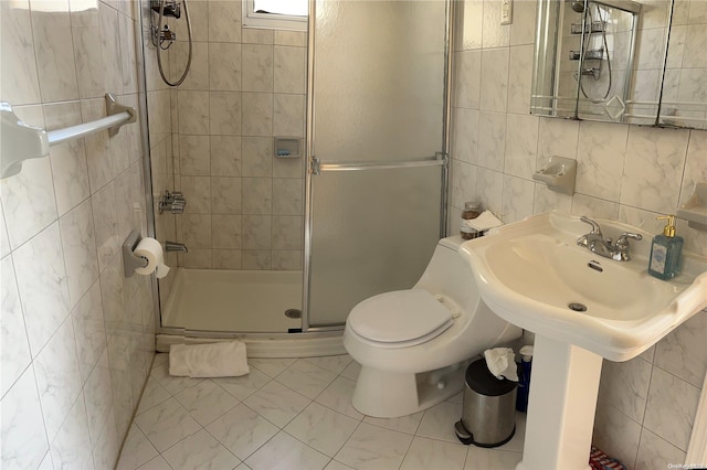 bathroom featuring sink, tasteful backsplash, toilet, a shower with door, and tile walls