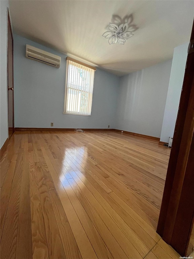 unfurnished room featuring a wall mounted AC, light hardwood / wood-style flooring, and a baseboard heating unit