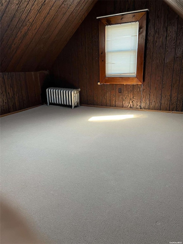 bonus room with carpet, lofted ceiling, radiator heating unit, wooden walls, and wood ceiling