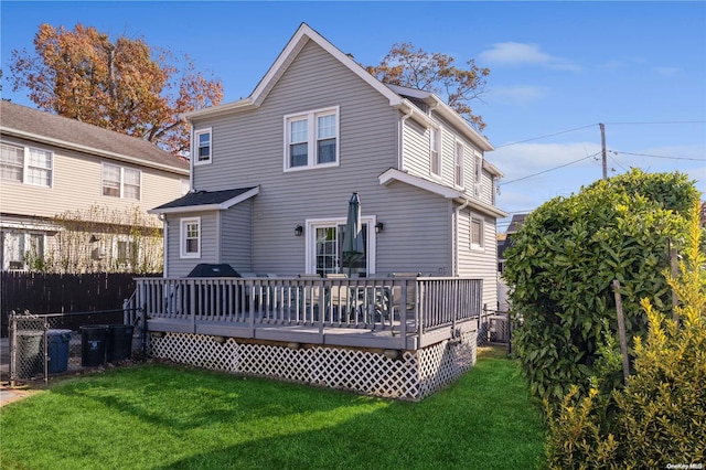 rear view of house featuring a lawn and a deck