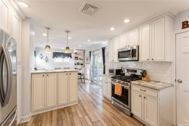 kitchen featuring pendant lighting, light wood-type flooring, appliances with stainless steel finishes, tasteful backsplash, and light stone counters