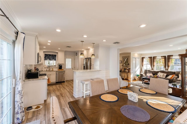 dining space with crown molding, sink, and light wood-type flooring