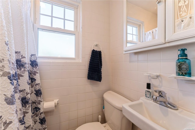 bathroom with tile walls, a healthy amount of sunlight, and sink