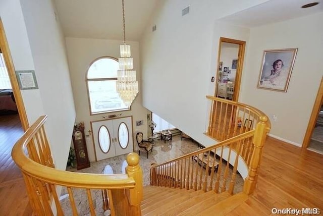 foyer featuring wood-type flooring, a towering ceiling, and a chandelier