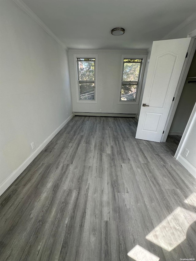 unfurnished bedroom with a baseboard heating unit, light hardwood / wood-style floors, and ornamental molding