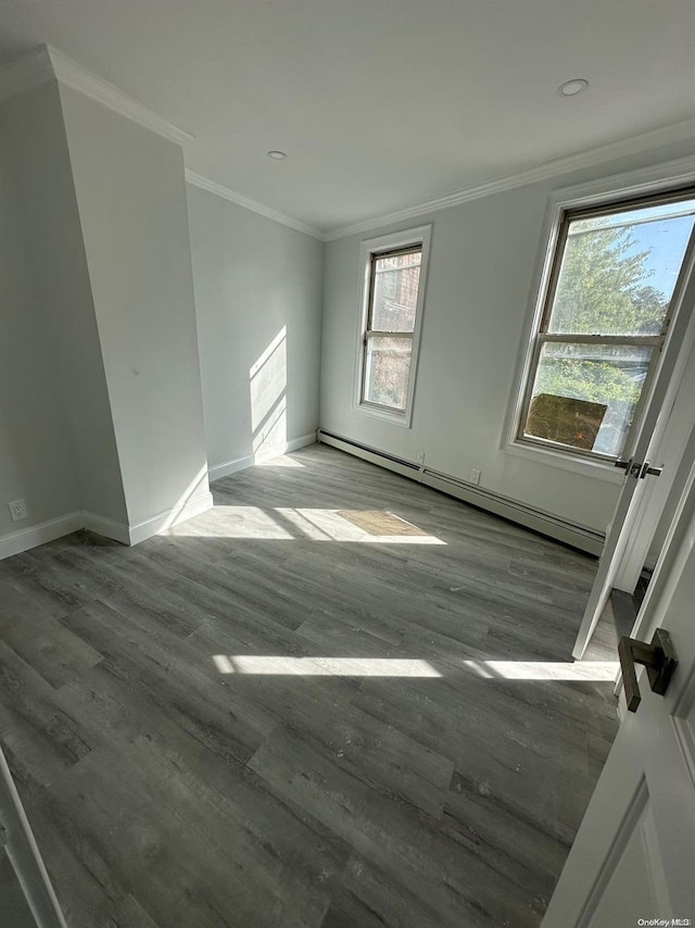 empty room with ornamental molding, dark wood-type flooring, and a baseboard heating unit