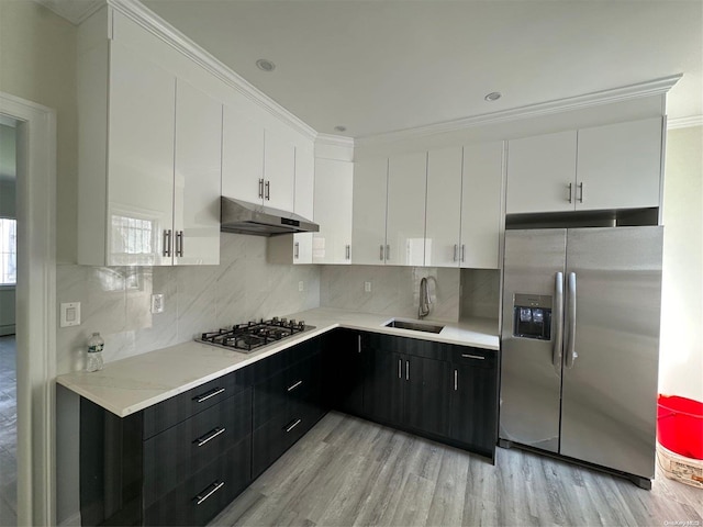 kitchen featuring white cabinetry, sink, stainless steel appliances, light hardwood / wood-style flooring, and backsplash