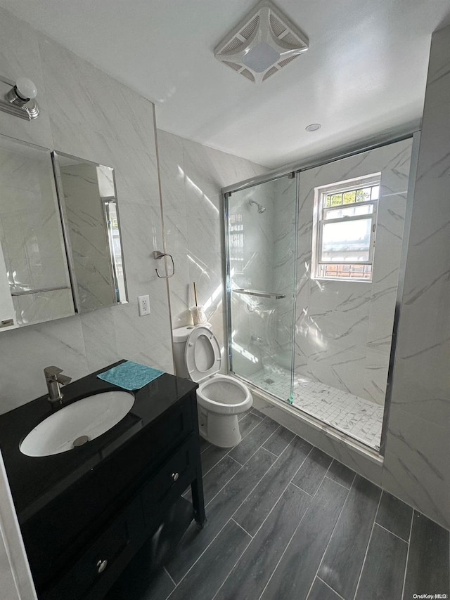 bathroom with vanity, toilet, walk in shower, and tile walls