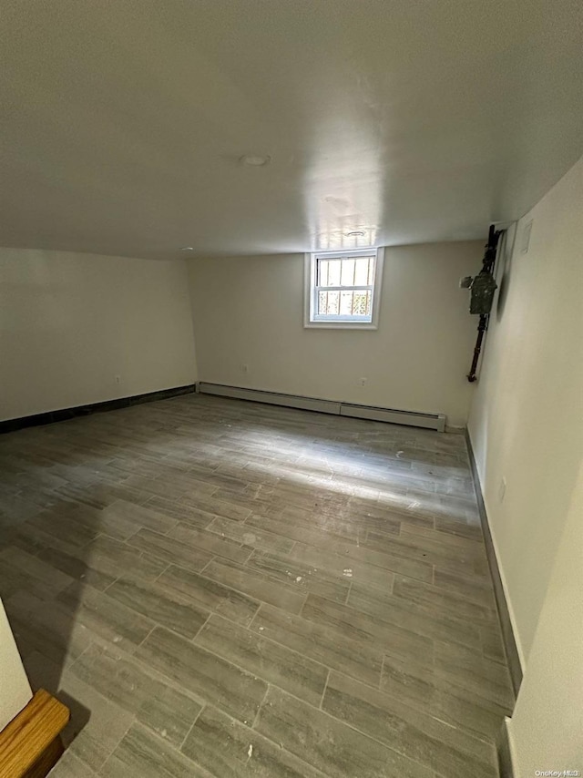 basement with a baseboard heating unit and light wood-type flooring