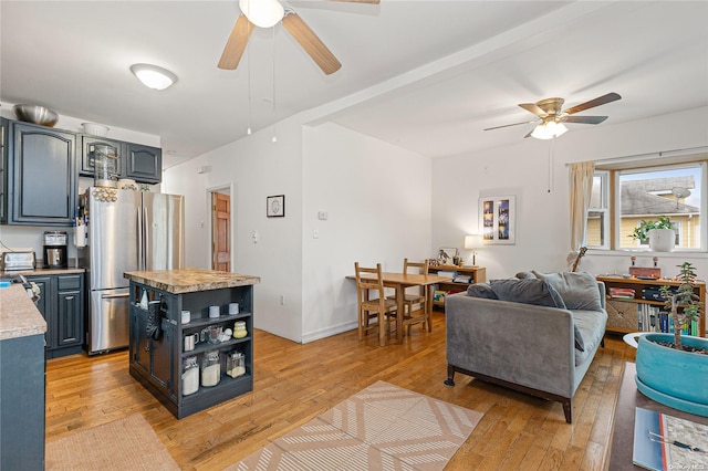 interior space with ceiling fan, a center island, light wood-type flooring, and stainless steel refrigerator